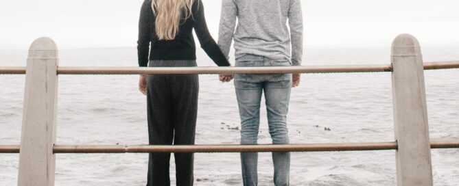 Romantic couple hold hands and look at the ocean